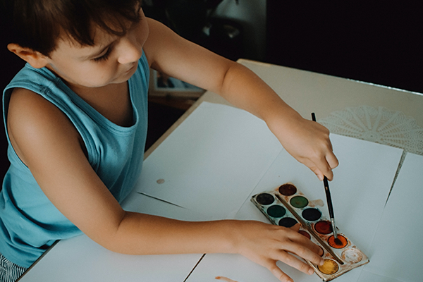 Niño pequeño pintando con acuarelas en casa
